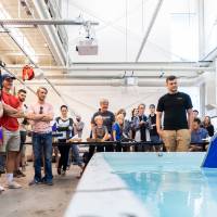 Participants watch a boat sail across the pool